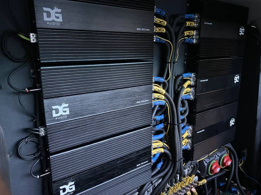 Wall of DG Audio 8000.1DG 2-ohm amplifiers with blue and yellow DG power cables